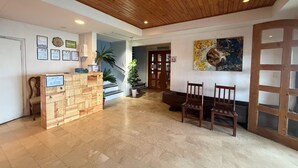 A reception area with a wooden reception desk, a staircase, and a painting on the wall. - Inntayon Lodge Baguio City (Baguio)
