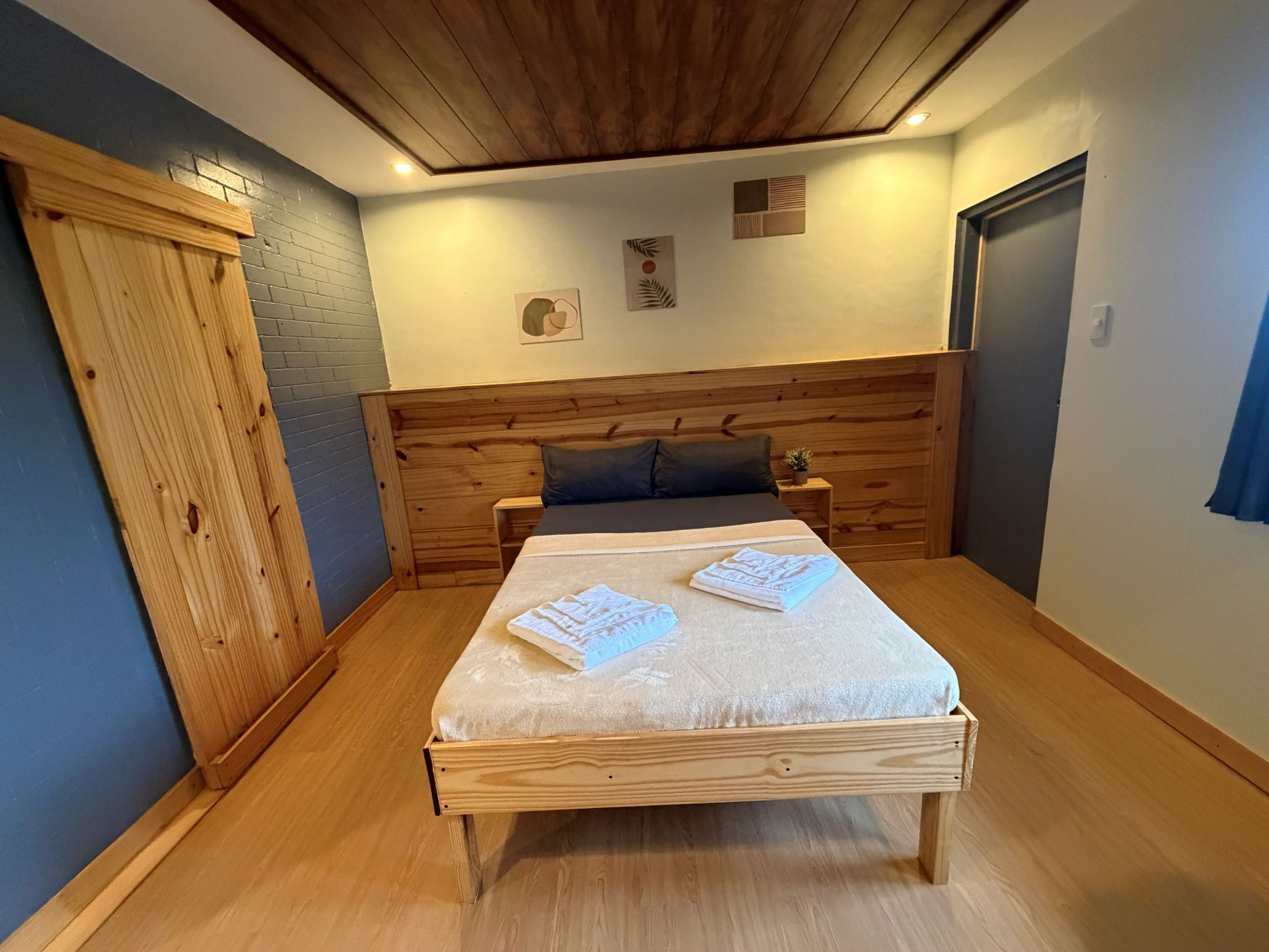 A bedroom with a wooden bed, a nightstand, a dresser, and a door.