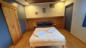 A bedroom with a wooden bed, a nightstand, a dresser, and a door.