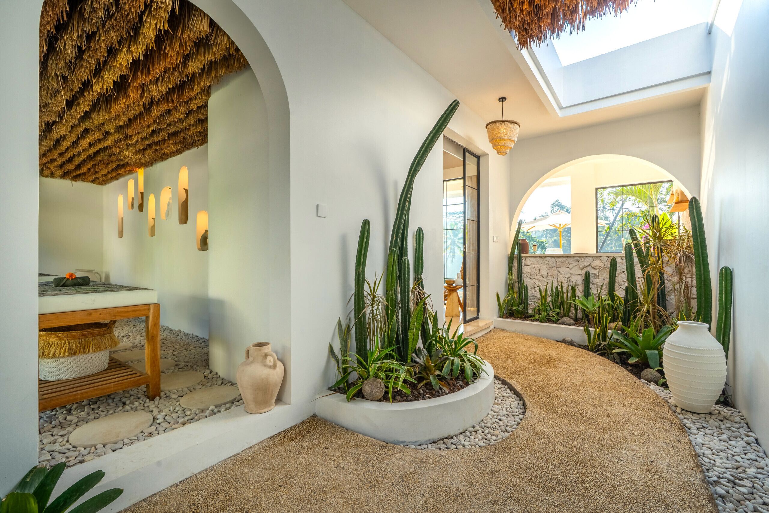 Un interior moderno con comedor, un sendero lleno de plantas y vistas al exterior.