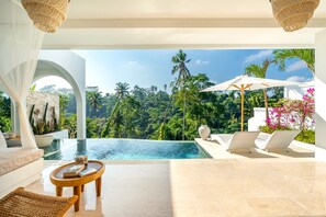 A modern infinity pool with a view of tropical trees, a white outdoor seating area with a table and chairs, and a large vase. - 2 Infinity Pools • Luxury Ubud 1br Villa • Jungle Paradise (Ubud)