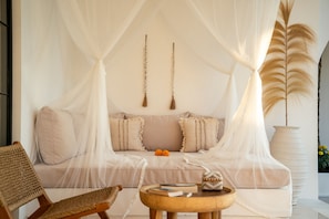 Ein Zimmer mit einer Couch, einem Sessel, einem kleinen Tisch und einer großen Pflanze.