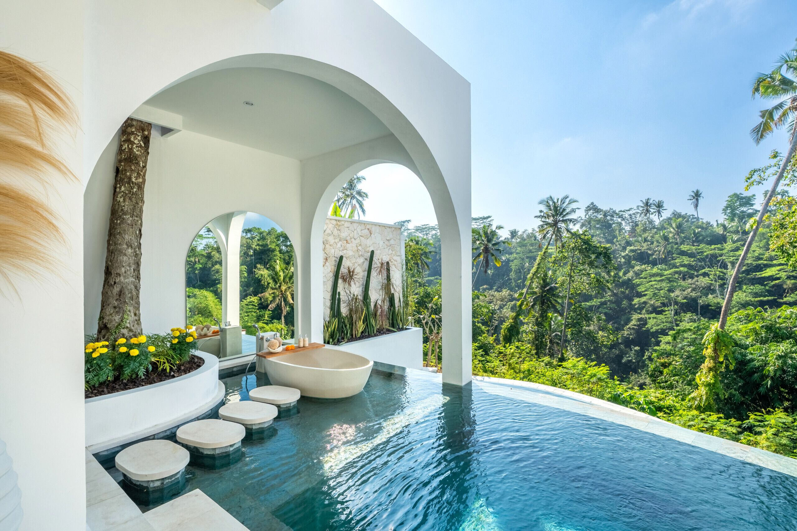 A modern infinity pool with a view of lush greenery and palm trees.