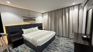 Ein Hotelzimmer mit Bett, Nachttischen, einem Flachbildfernseher und einem großen Fenster mit Vorhängen.