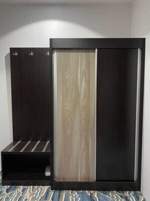 Una habitación con un armario oscuro, un panel de madera y una estantería.