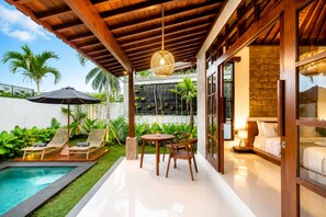 A modern outdoor patio with a pool, lounge chairs, and a dining area. - Kecak Bali Villa  (Gianyar)
