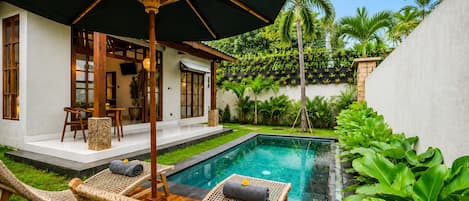 A poolside area with lounge chairs, a table, and a covered seating area.