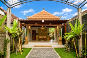 A traditional pavilion with a tiled roof, a stone wall, and a welcome mat. - Kecak Bali Villa  (Gianyar)