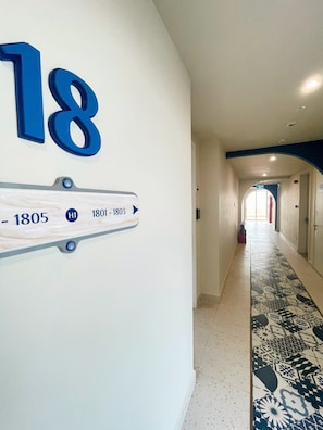 Corredor com placa de sinalização indicando números de quartos e datas.