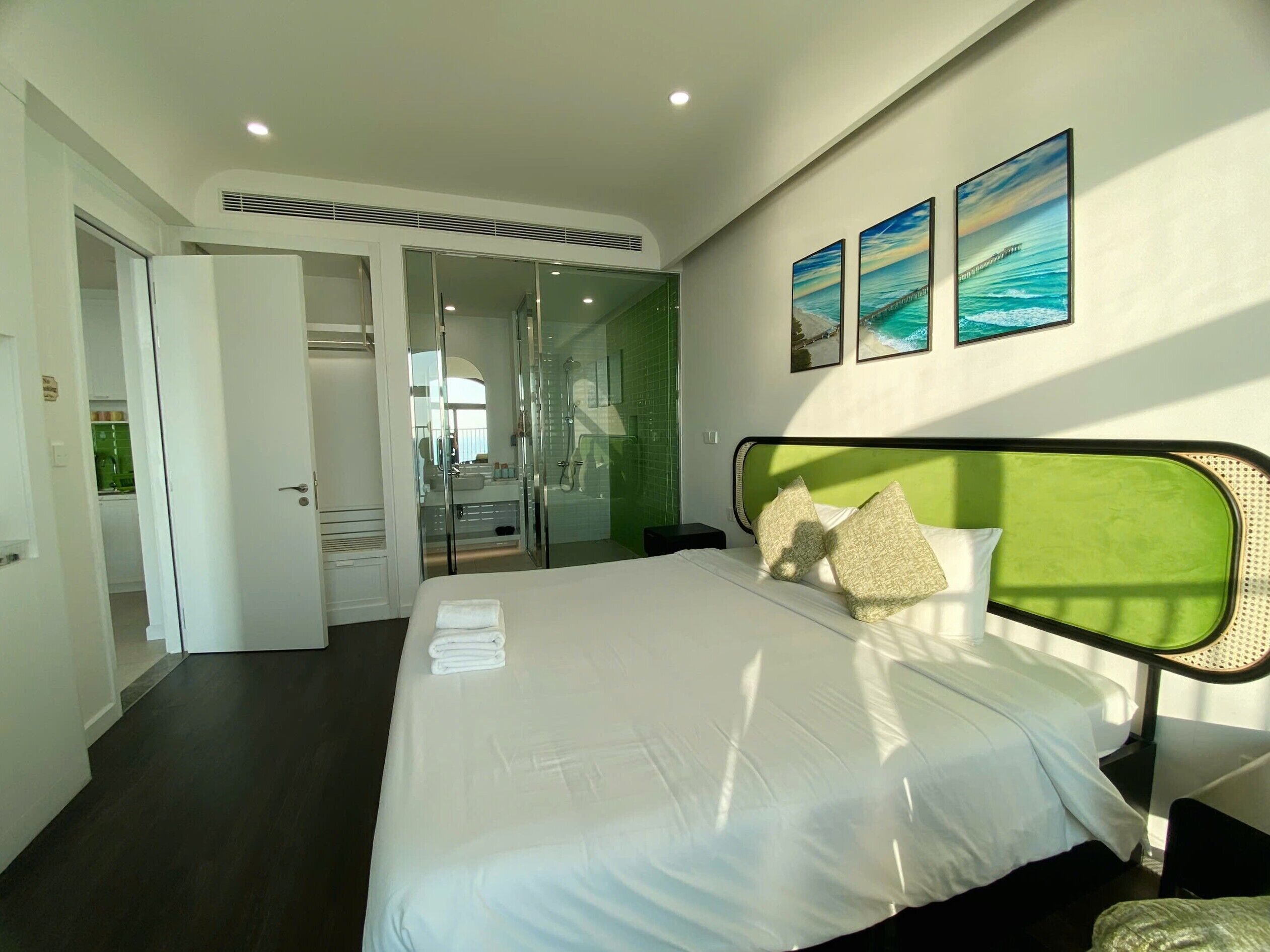 A hotel room with a bed, a walk-in closet, a glass-enclosed shower, and artwork on the wall.