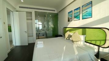A hotel room with a bed, a walk-in closet, a glass-enclosed shower, and artwork on the wall.