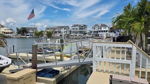 A marina with boats docked, a white pier, and houses in the background. - Palm Trees & Great Sunsets! Exclusive Bayfront w/ Huge Outdoor Living Area&Docks (Stone Harbor)