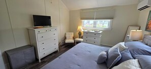 A bedroom with a bed, a dresser, a chair, a desk, a television, and a window with blinds. - Palm Trees & Great Sunsets! Exclusive Bayfront w/ Huge Outdoor Living Area&Docks (Stone Harbor)