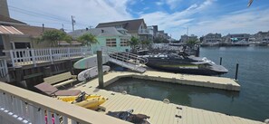 A marina with boats docked, a wooden deck, and a view of residential buildings. - Palm Trees & Great Sunsets! Exclusive Bayfront w/ Huge Outdoor Living Area&Docks (Stone Harbor)