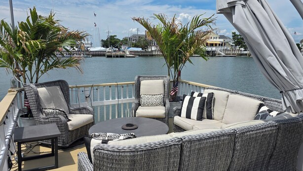 A deck with wicker furniture, a table, and a view of the marina. - Palm Trees & Great Sunsets! Exclusive Bayfront w/ Huge Outdoor Living Area&Docks (Stone Harbor)
