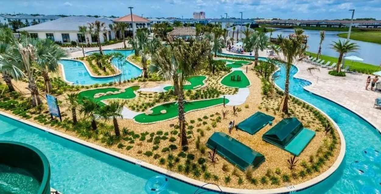Área de piscina com campo de golfe, espreguiçadeiras e vista para um corpo de água.