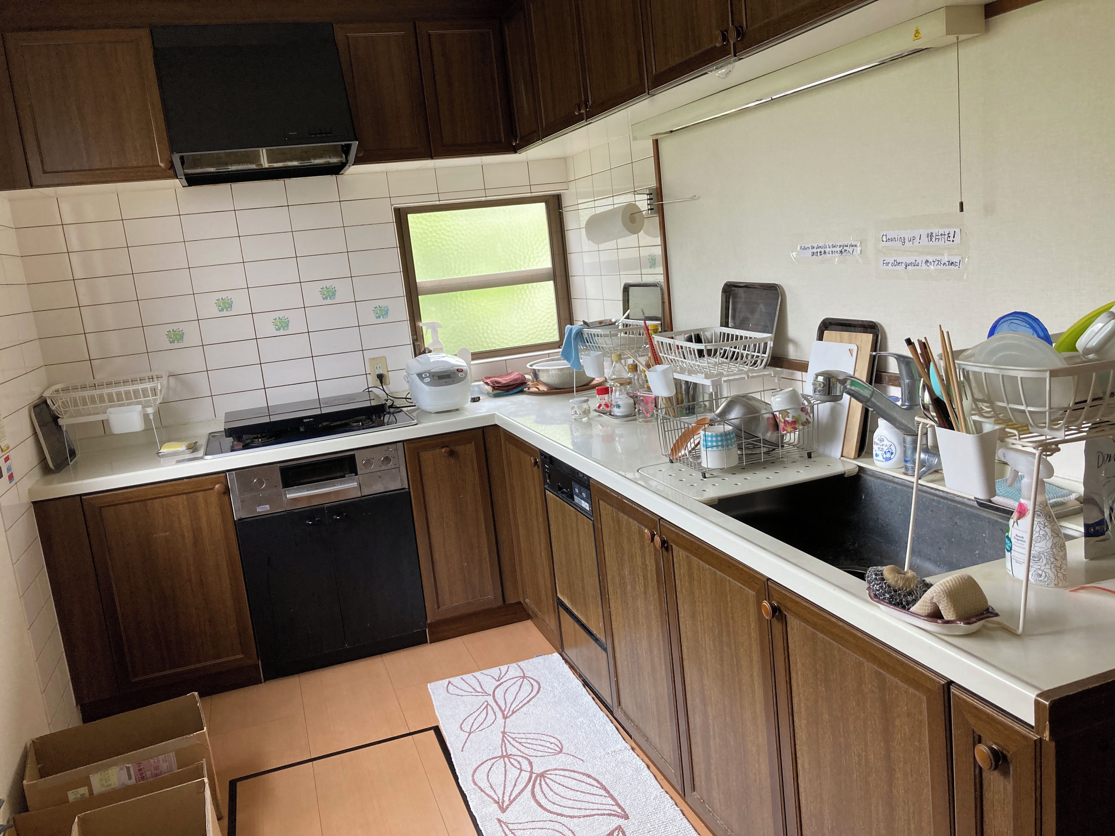 A kitchen with wooden cabinets, a white countertop, a window, and various kitchen appliances.