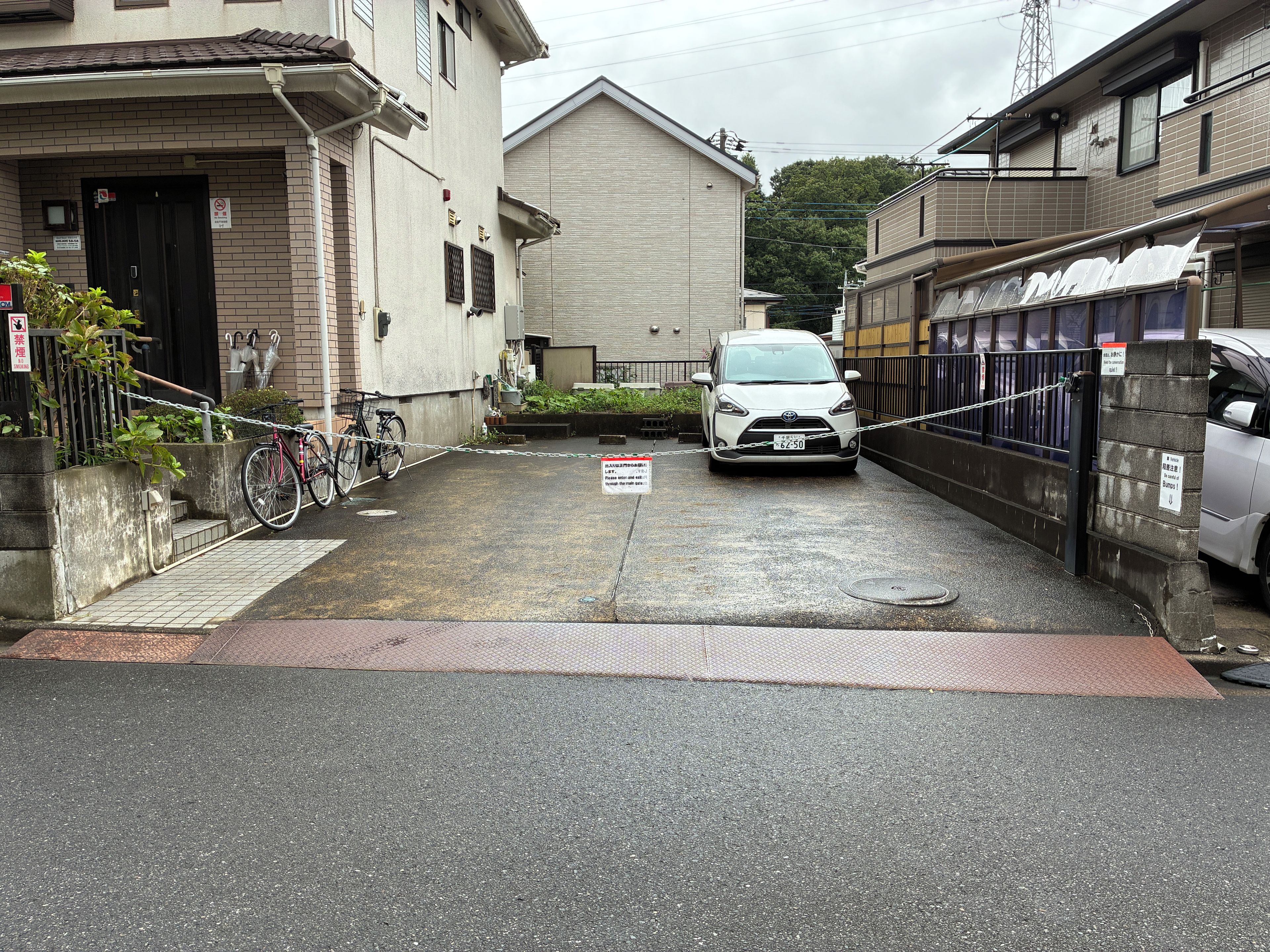 A narrow street with a parked car and a bicycle.