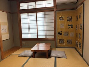 Una habitación japonesa tradicional con suelo de tatami, una mesa de madera baja y puertas correderas shoji.