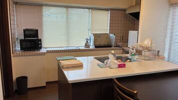A kitchen with a microwave, a sink, and a window with blinds.
