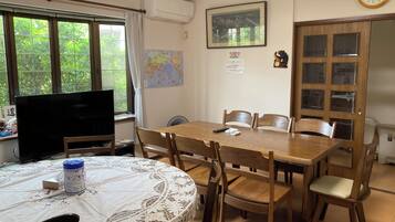 A dining area with a round table, chairs, a television, and a map on the wall.