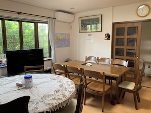 A dining area with a round table, chairs, a television, and a map on the wall. - MORE&MORE (Sakura)