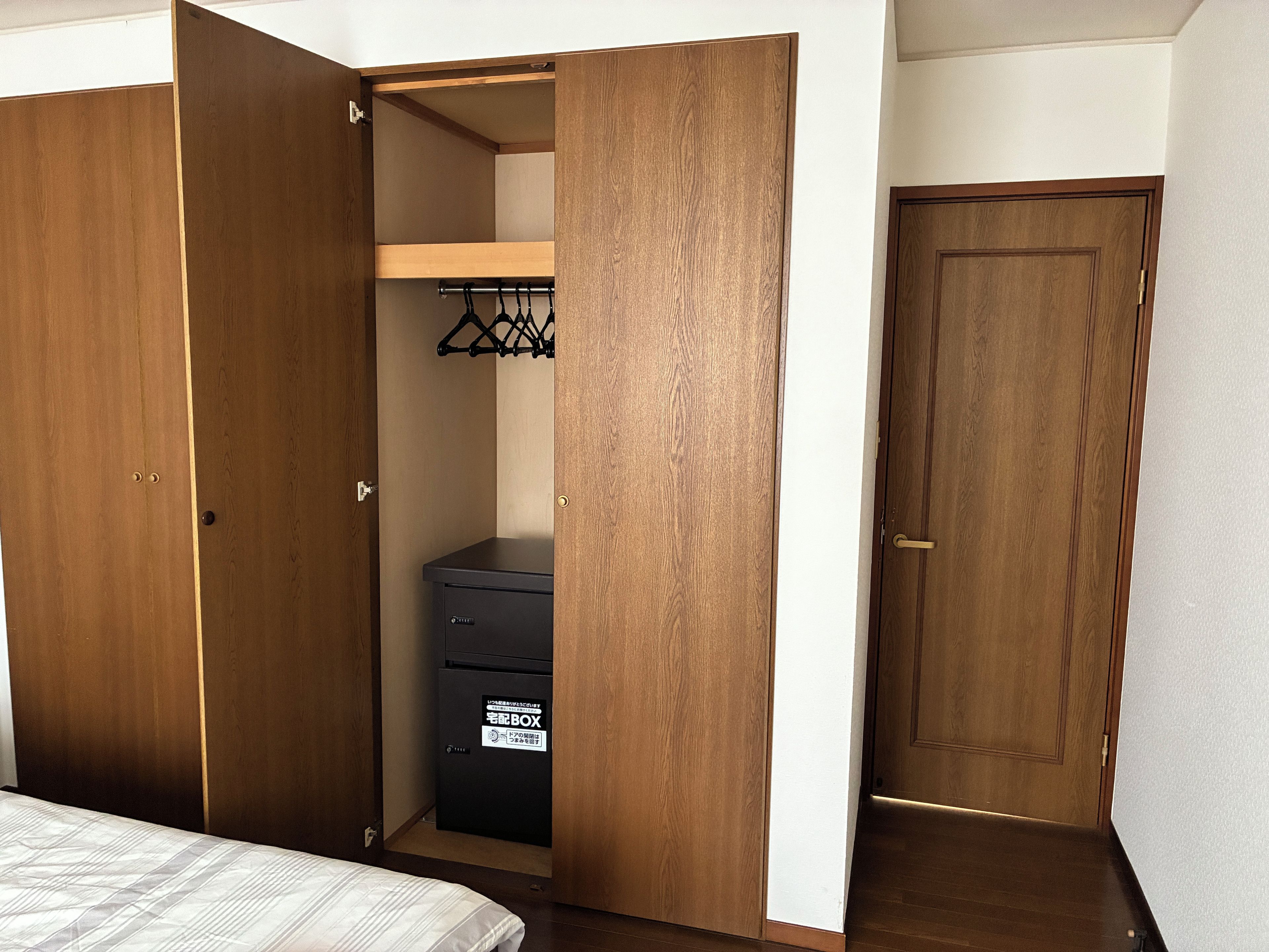 A bedroom with a bed, a wardrobe, and a small storage unit.