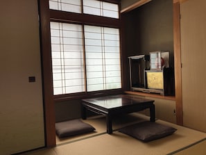 Una habitación japonesa tradicional con suelo de tatami, una mesa de madera baja y puertas correderas shoji.