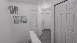 A hallway with white doors, a vent, and a framed picture on the wall.