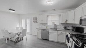 A kitchen with white cabinets, a dishwasher, a stove, and a microwave.