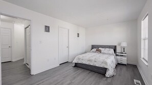 Un dormitori amb un llit, fallegueres, una finestra i una porta.