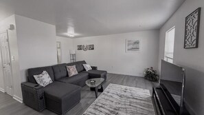 Ein modernes Wohnzimmer mit einer Eckcouch, einem Couchtisch und einem Flachbildfernseher.