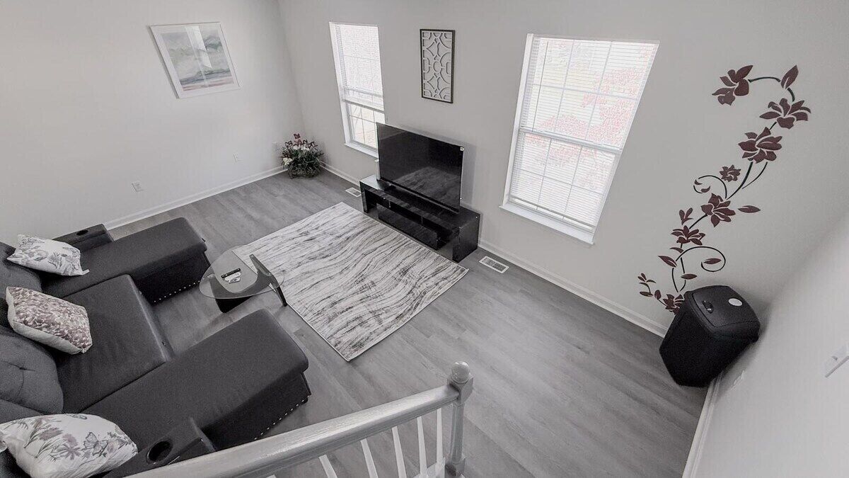 Una sala moderna con un conjunto de sofás, un televisor de pantalla plana y una planta decorativa.