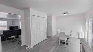 Un saló modern amb un sofà, una taula de dinar amb cadires i una porta blanca.