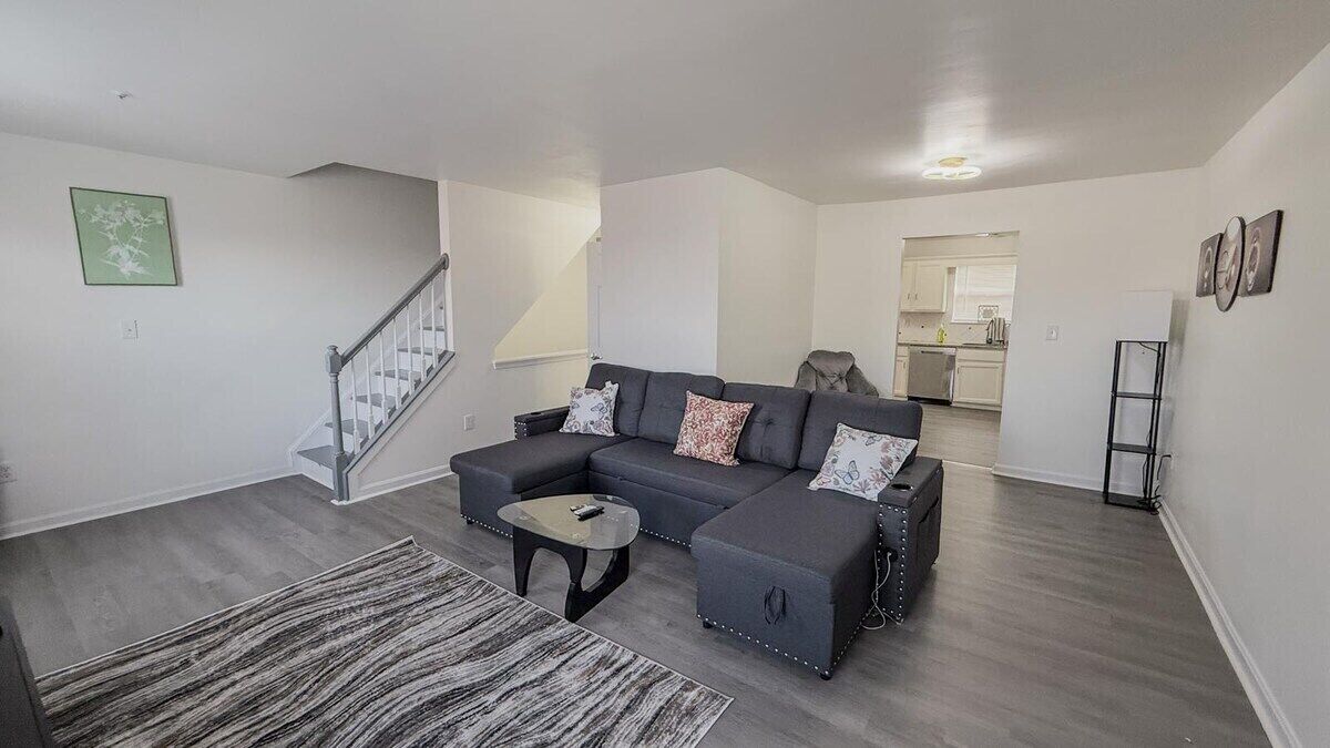 A modern living room with a sectional sofa, a coffee table, and a staircase.