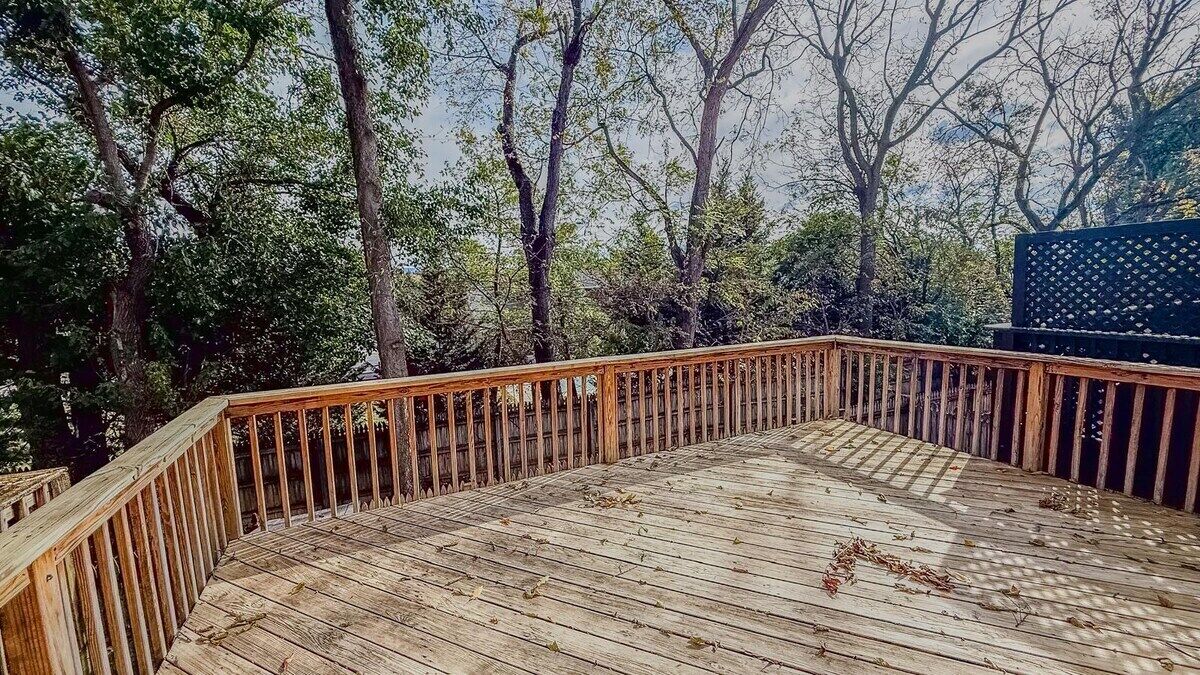 A wooden deck with a railing, surrounded by trees.