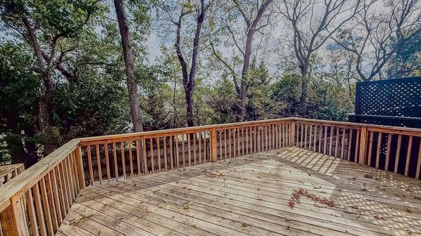 A wooden deck with a railing, surrounded by trees.