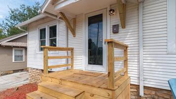 A wooden front porch with steps leading to a door, a mailbox, and a house number 1018.