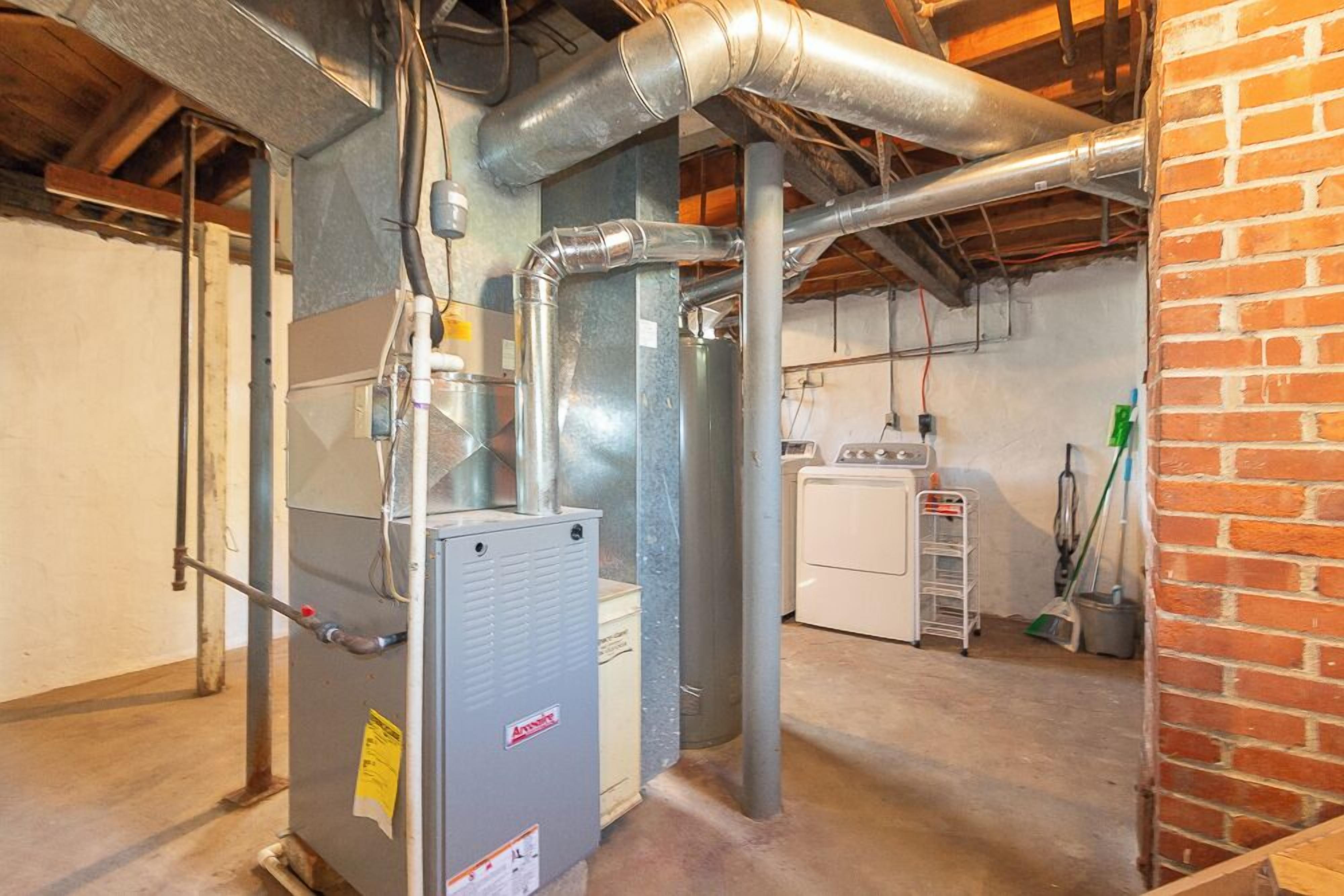 A utility room with a water heater, ductwork, and a laundry area.