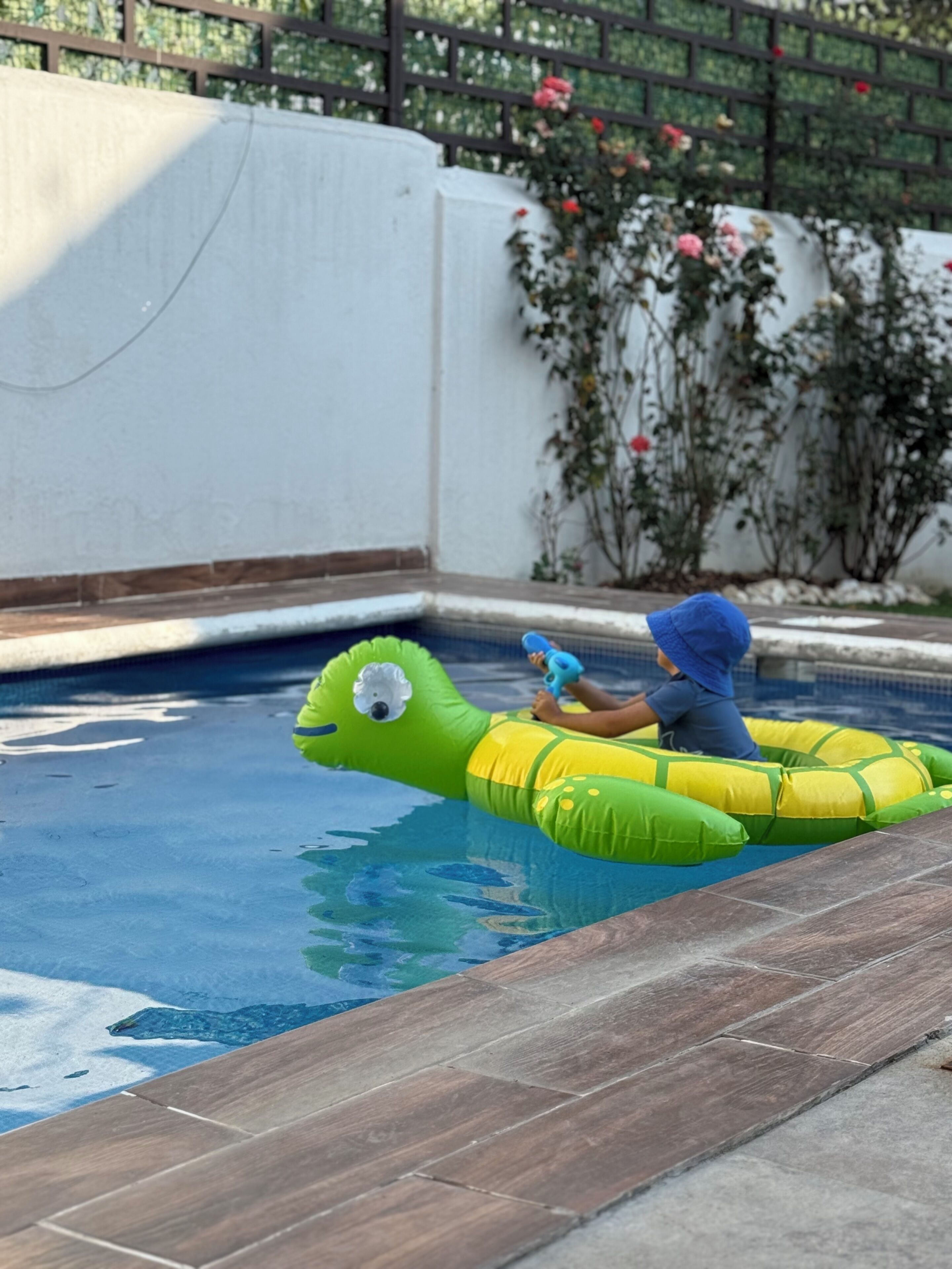 Une piscine dans laquelle une personne flotte sur un matelas gonflable vert.