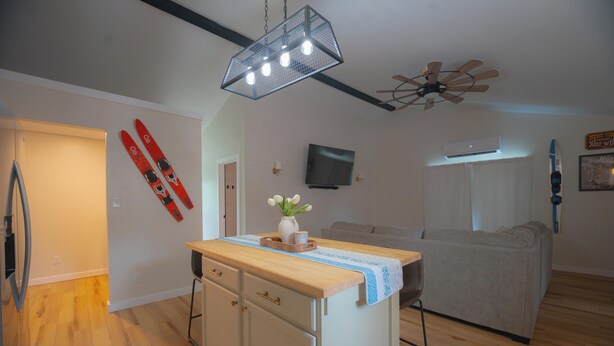 A compact living space with a kitchenette, a ceiling fan, a mounted TV, and a ski-themed decoration. - Charming outdoor getaway (Jay)
