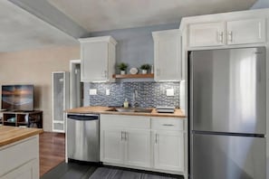 A modern kitchen with white cabinetry, a stainless steel refrigerator, and a tiled backsplash.