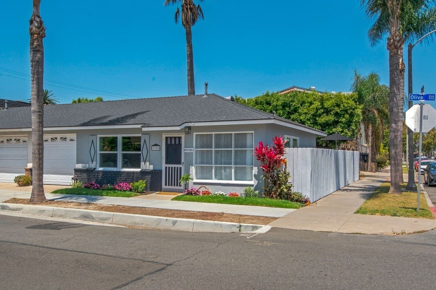 Une maison de plain-pied avec un garage, un porche à l ’avant et un petit jardin devant la maison, agrémenté de fleurs.
