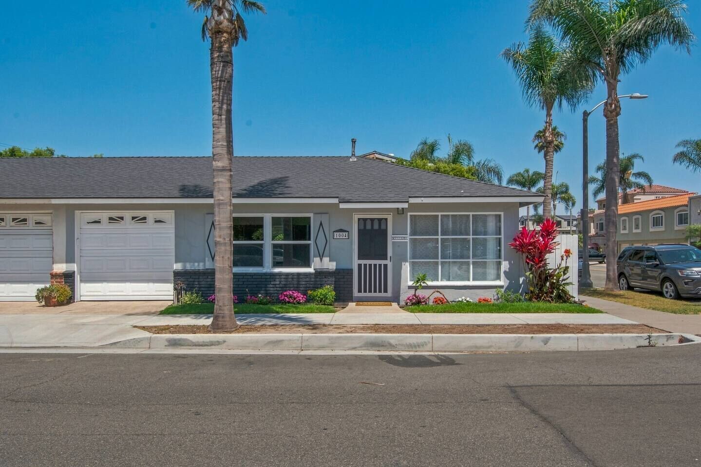 A single-story house with a garage, a front porch, and a small garden with flowers.