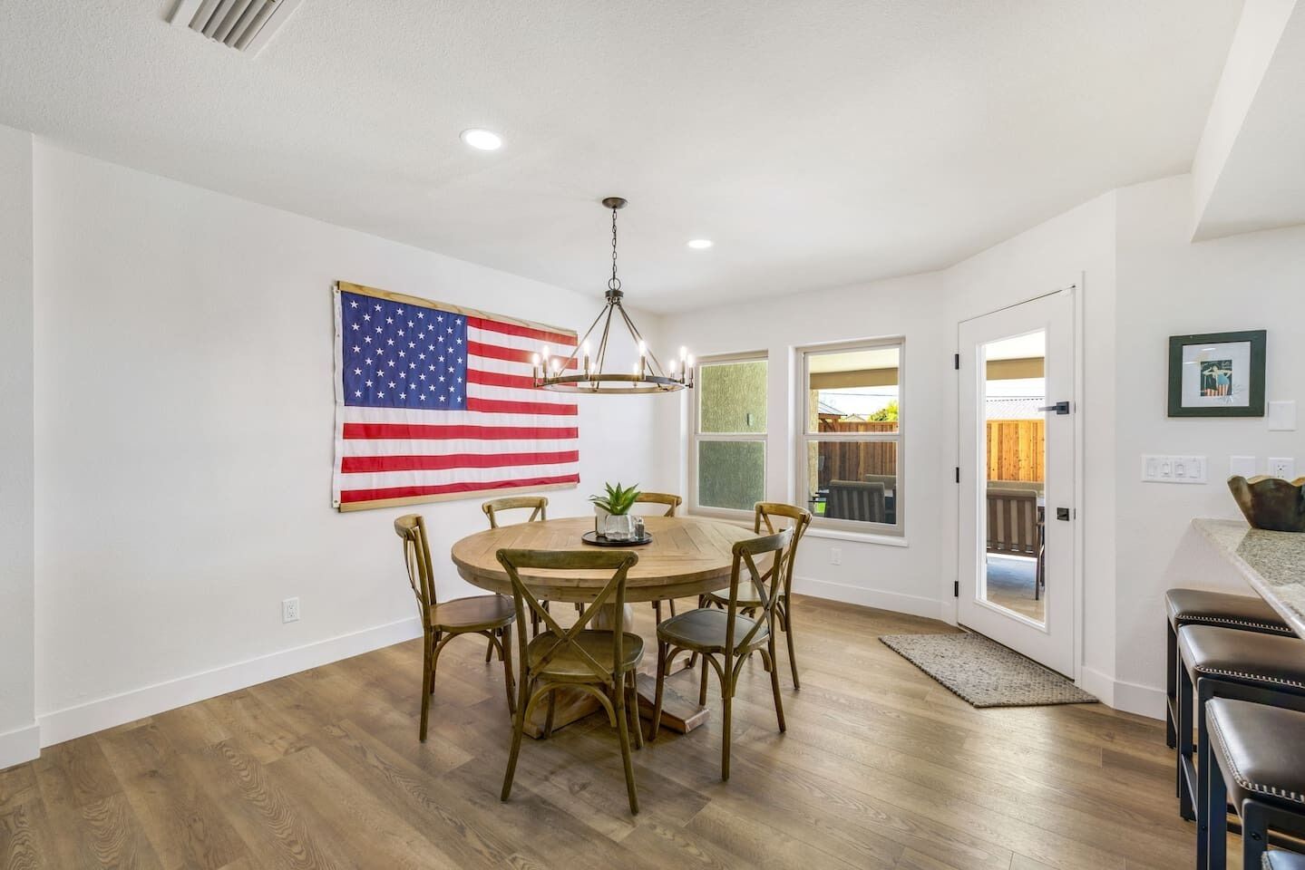 Uma sala de jantar com uma mesa redonda, cadeiras e uma bandeira americana na parede.