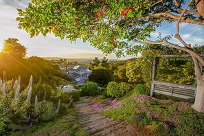 Ein Wohnhaus mit einer Holztreppe, üppigem Grün und Blick auf ein Haus im Hintergrund.