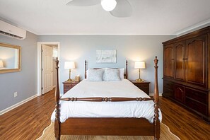 A bedroom with a large bed, two bedside tables, a wardrobe, and a ceiling fan.