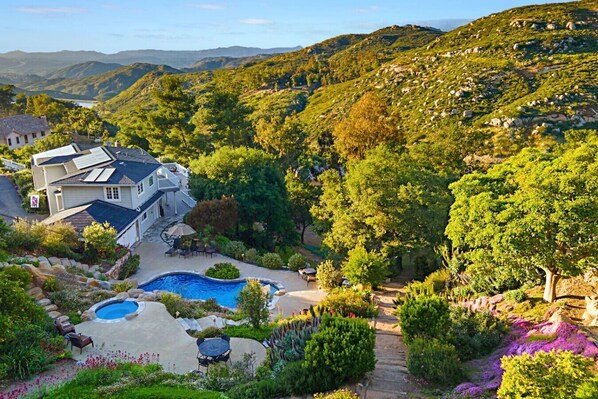 A residential property with a swimming pool, a patio, and a view of the surrounding hills.