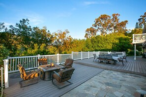 An outdoor deck with a fire pit, seating area, and a covered section with tables and chairs.