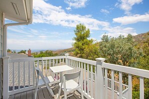 Ein Balkon mit weißer Brüstung, einem Tisch und zwei Stühlen.